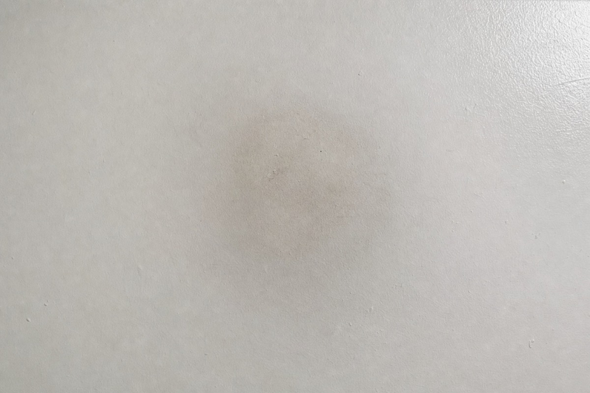 Jemný sivý tieň sadzí na bielom strope nad miestom, kde stála parafínová sviečka